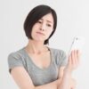 スマホを見ながら悩む女性